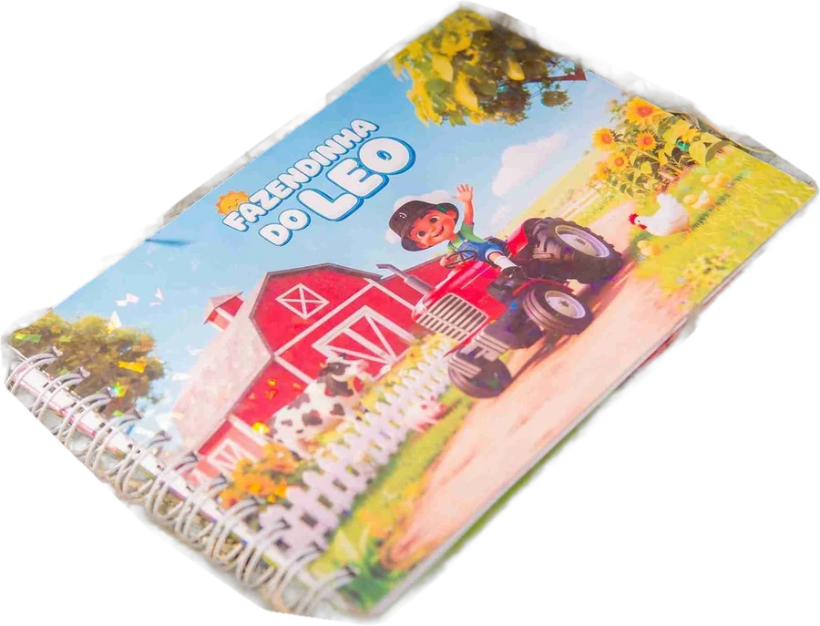 O livrinho Fazendinha do Léo, em espiral. Na capa, o Leozinho de boné acena de cima de um trator vermelho na frente do celeiro.